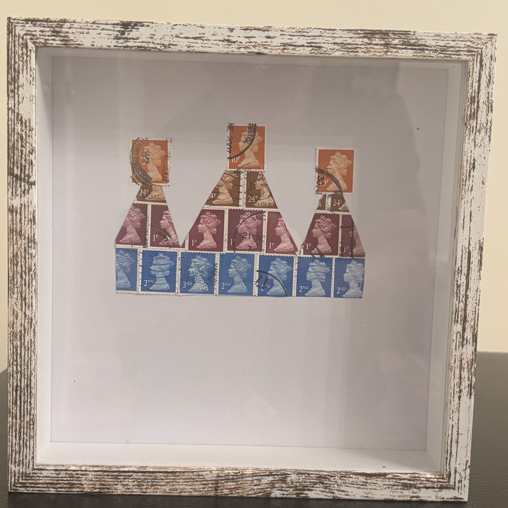 The Crown Jewels framed postage stamp art — three crowns built from vintage British Machin stamps of Queen Elizabeth II in a weathered white 8x8 shadow box